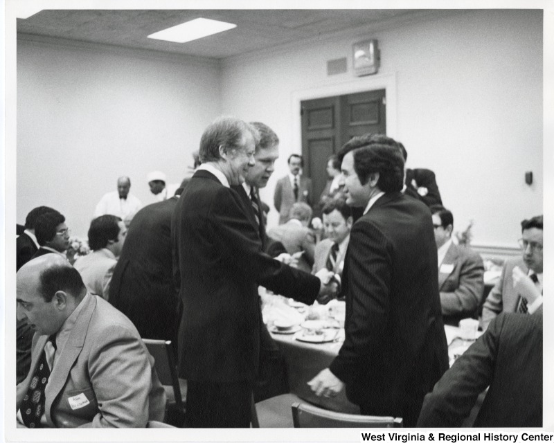 From left to right: Congressman Adam Benjamin (D-IN) seated, President Jimmy Carter, Congressman Norman Dicks (D-WA), and Congressman Nick Rahall II (D-WV) shaking President Carters hand. This was at a new member function.